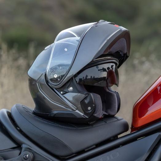 motorcycle helmets and leather gear displayed on a wooden table in warm sunlight