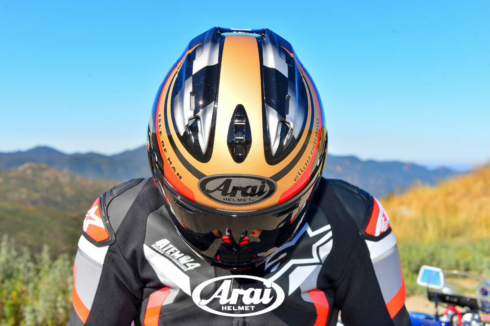 Person wearing a colorful Arai motorcycle helmet with a scenic background
